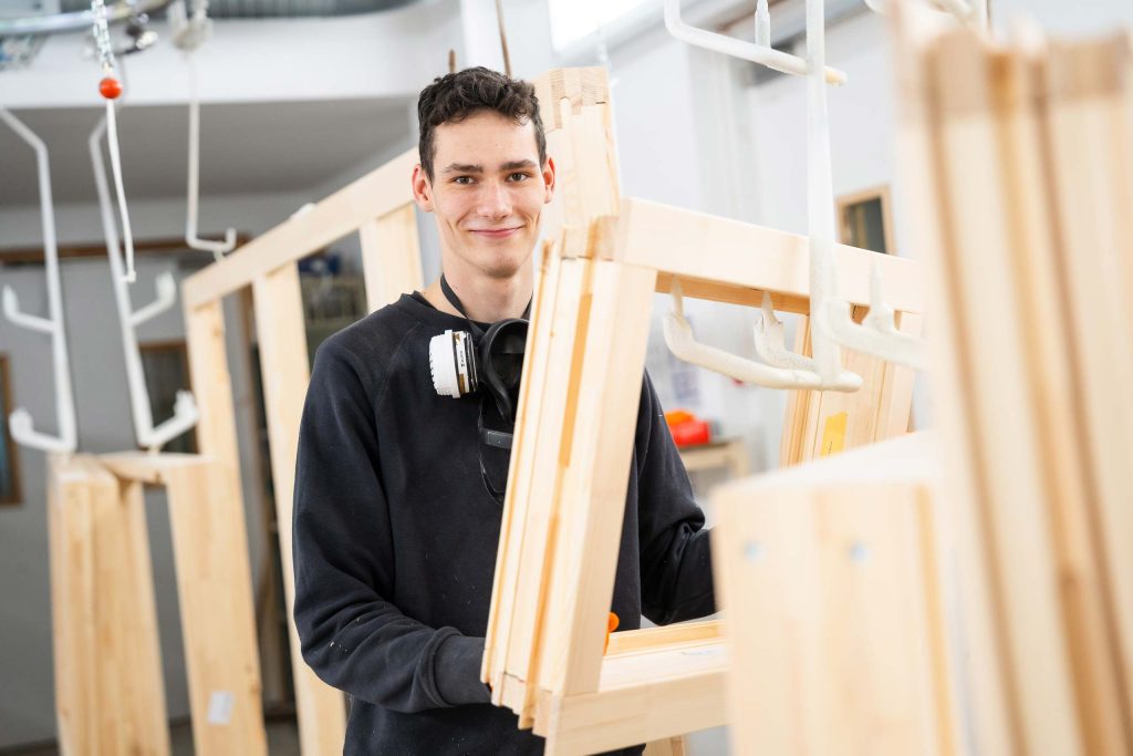 mitarbeiter hängt holzfensterrahmen zum trocknen auf